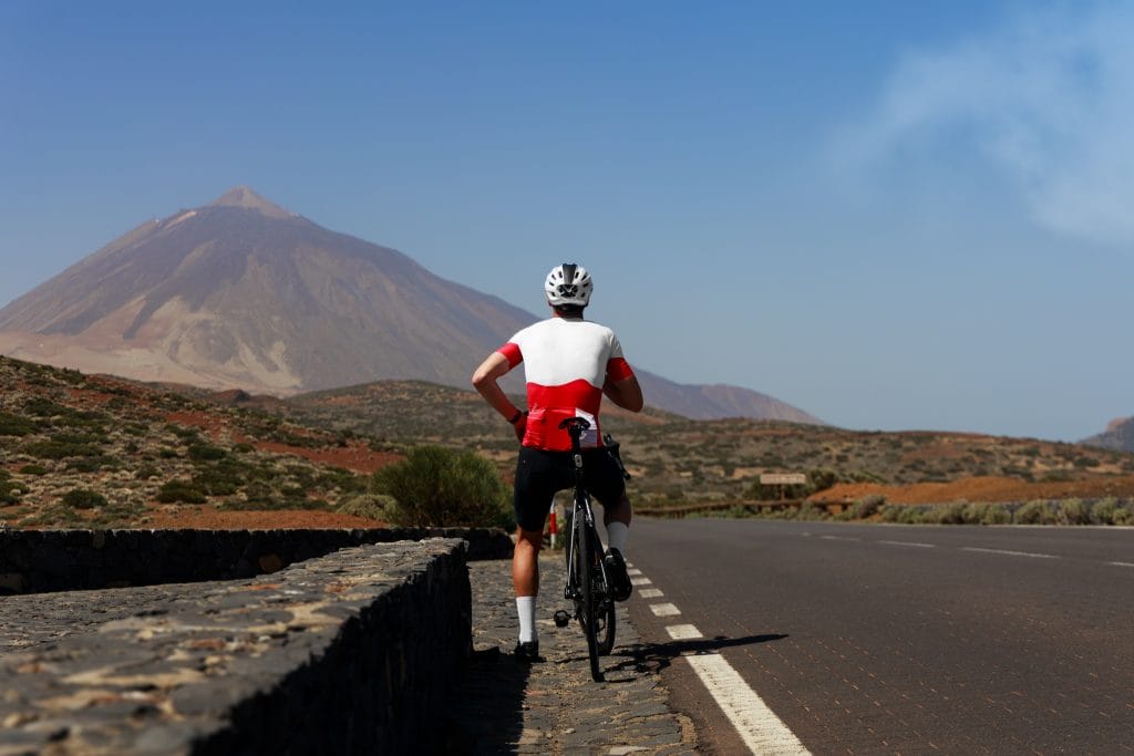 A cyclist pauses amidst beautiful volcanic landscape during a self-guided cycling holiday in Tenerife