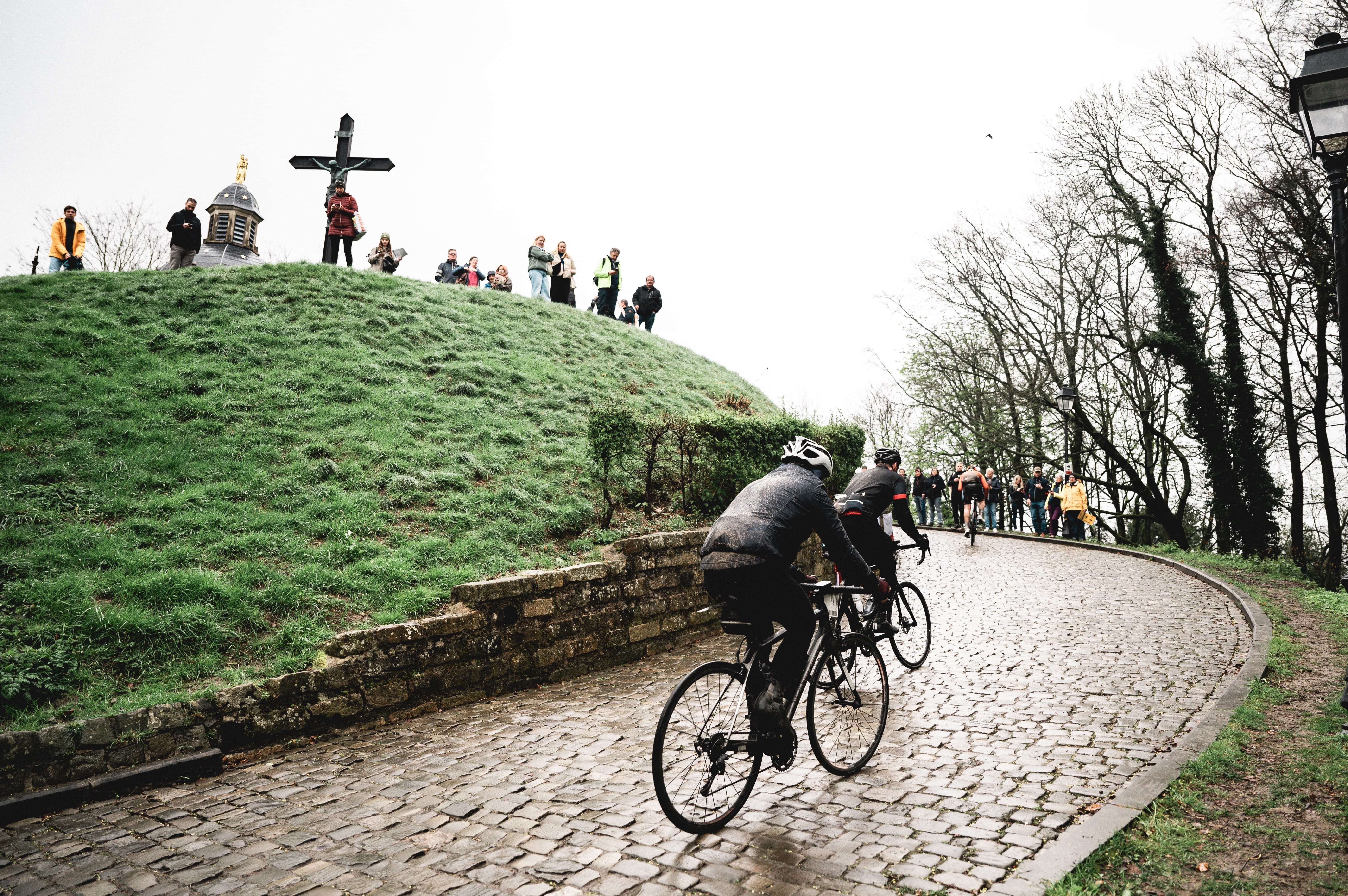 Riders pass a monument to the fallen during the Spring Classics trip
